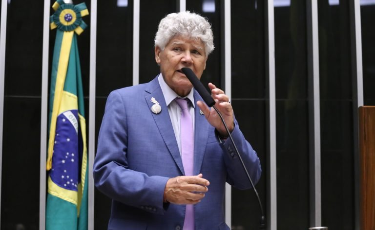 Deputado Chico Alencar fala ao microfone. Ele é claro, tem o cabelo cacheado e grisalho, e usa um terno cinza