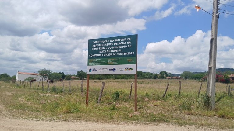 Placa informativa verde sobre a construção do sistema de abastecimento de água na zona rural de Mata Grande, Alagoas.
