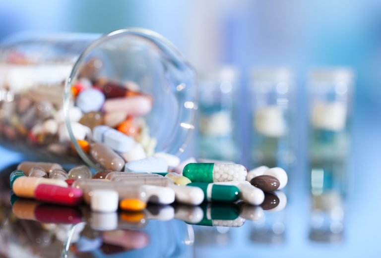 Medicamentos – comprimidos, drágeas e pílulas – misturados e espalhados em cima de uma superfície espelhada