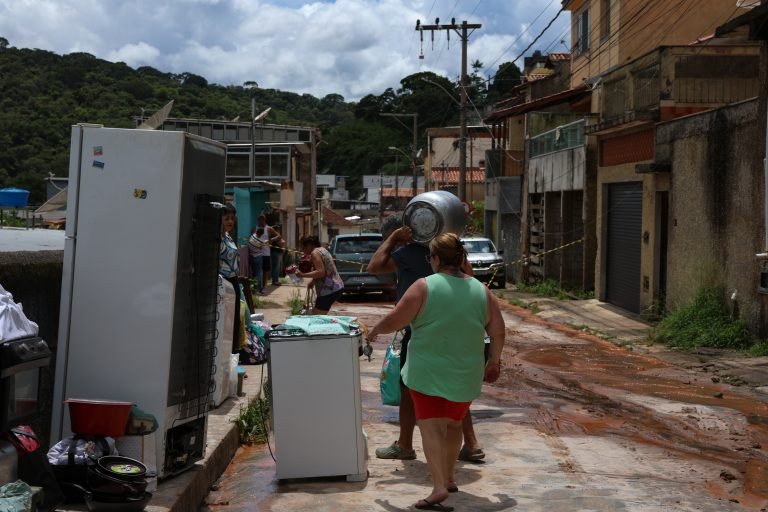Pessoas nas ruas com móveis que tiraram de suas casas após as intensas chuvas na Zona da Mata, em Minas Gerais